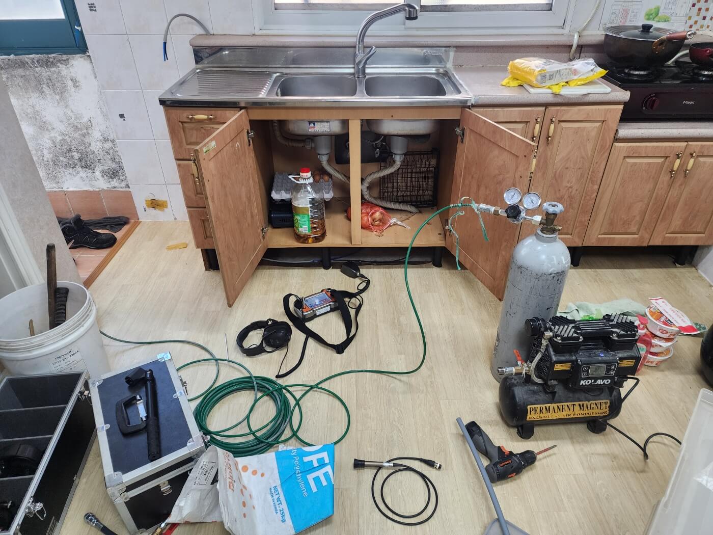 누수탐지 장비로 주방 배관을 점검하는 모습